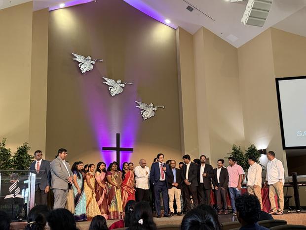 The fellowship gathered on stage before the lit cross
