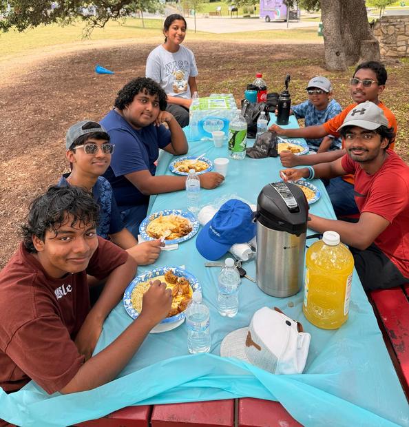 Youth of the fellowship sharing a meal at an outdoor picnic table