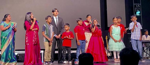 Adults and children singing together on stage