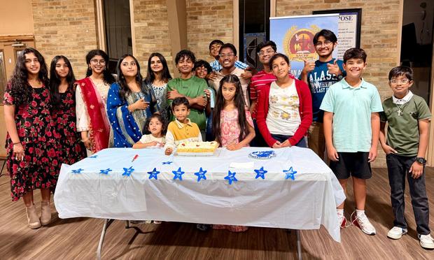 Children and youth gathered around a decorated cake table