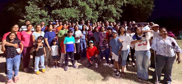 The fellowship together outdoors under the oak trees
