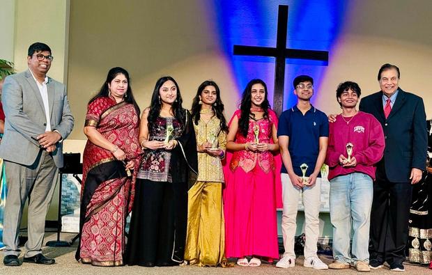 Youth in festive dress on stage before the lit cross