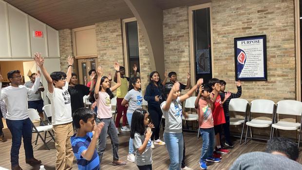 Children worshipping with hands raised at a Saturday service