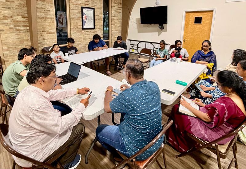 The fellowship studying the Bible together around tables