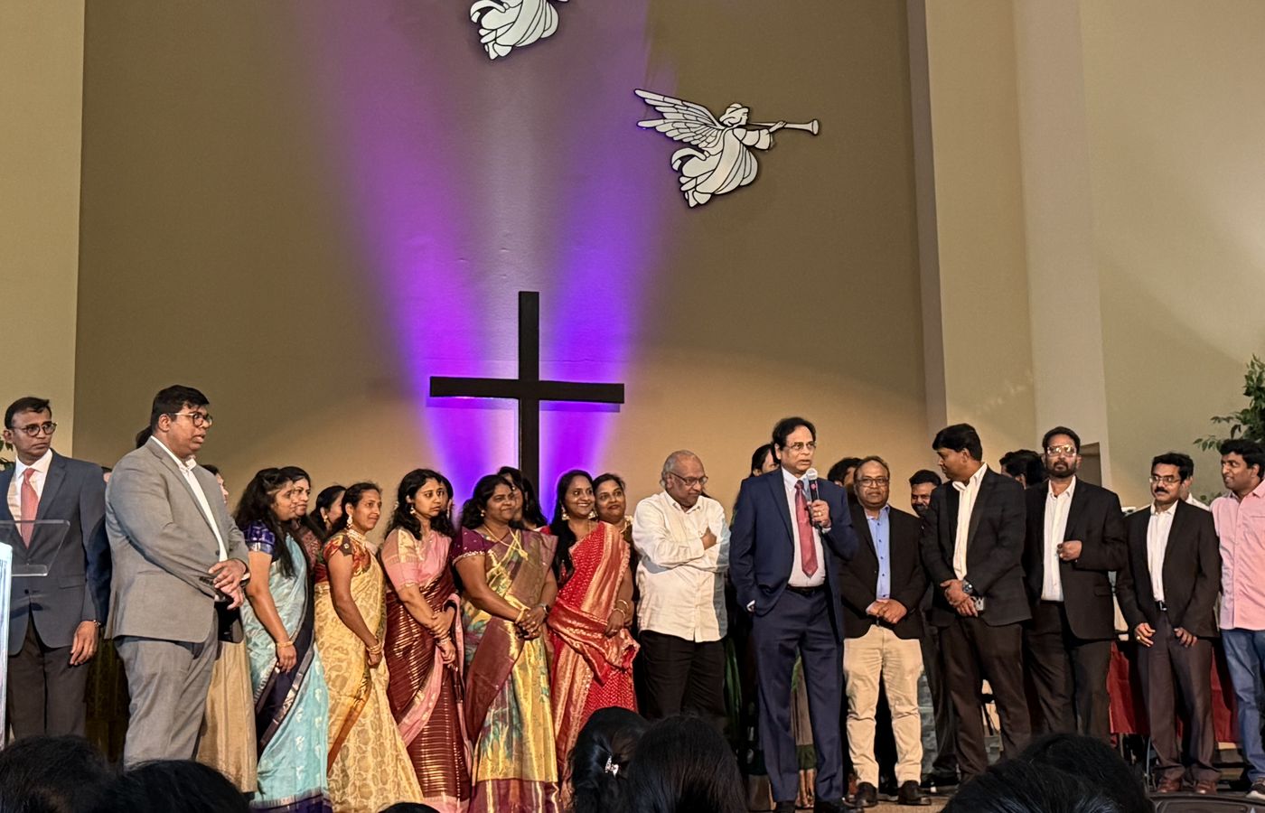 The SACFF fellowship gathered on stage before the lit cross during a worship service